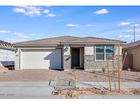 Charming single-story home with stone accents, a two-car garage, and a well-maintained front yard under a blue sky at 16766 W Yucatan Dr, Surprise, AZ 85388