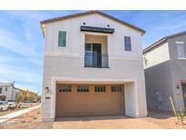 Two-story home featuring a tan garage door, white exterior, and small balcony on the second floor at 2434 W Rowel Rd, Phoenix, AZ 85085
