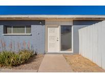 Charming front entrance with a white door, xeriscaping, and painted brick exterior in blue at 7508 W Osborn Rd, Phoenix, AZ 85033