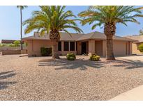 Ranch style home with desert landscaping and two palm trees in the front yard at 13223 W Jubilee Dr, Sun City West, AZ 85375