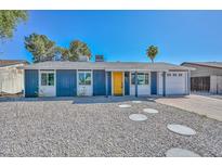 Charming single-story home features a blue exterior, a bright yellow front door, and low-maintenance landscaping at 3801 E Captain Dreyfus Ave, Phoenix, AZ 85032