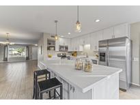 Modern white kitchen featuring an island with pendant lights and stainless steel appliances at 9827 W Palmer Dr, Sun City, AZ 85351