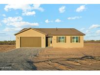 A single-story tan home with a brown roof, brown shutters, and a two-car garage under a cloudy blue sky at 31824 N 221St Dr, Wittmann, AZ 85361