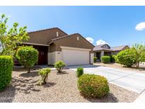 Single-story home with a two-car garage and a well-manicured front yard featuring mature landscaping at 18147 W Ida Ln, Surprise, AZ 85387