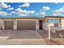 New home exterior featuring a two-car garage and stone accents at 17841 W Blue Sky Dr, Surprise, AZ 85387