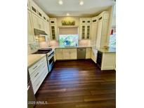 Bright kitchen with ample cabinetry, stainless steel appliances, and dark hardwood floors at 6979 E Mighty Saguaro Way, Scottsdale, AZ 85266
