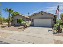 Charming single-story home featuring a two-car garage, desert landscaping, and an American flag at 34 N Agua Fria Ln, Casa Grande, AZ 85194