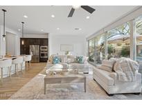 Bright living room featuring modern furniture, neutral tones, ceiling fan, and sliding glass doors to outdoor living space at 23379 N 73Rd Way, Scottsdale, AZ 85255