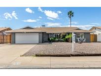 Charming single-story home with a well-manicured front yard, complemented by a white two-car garage and desert landscaping at 3425 W Acoma Dr, Phoenix, AZ 85053