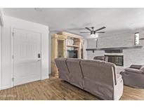 Inviting living room featuring a decorative fireplace, ceiling fan, and stylish cabinet with storage at 728 W Grove Cir, Mesa, AZ 85210