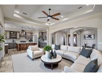 Open-concept living space with a sleek sectional sofa and views into the modern kitchen at 29923 W Melvin St, Buckeye, AZ 85396