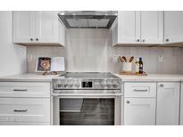 Modern kitchen with stainless steel oven, bright countertops, white cabinets, and tile backsplash at 2126 E Watson Dr, Tempe, AZ 85283
