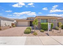 Charming single-story home with a well-manicured front yard and a brick driveway, under a bright blue cloudy sky at 28389 N 131St Dr, Peoria, AZ 85383