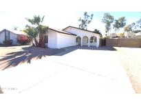 Single-story home boasting desert landscaping, arched porch, and a spacious driveway leading to an attached garage at 1446 S Revere --, Mesa, AZ 85210