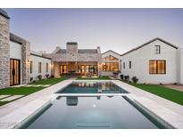 An elevated rear view of a backyard pool and stone patio surrounded by lush artificial lawn at 9810 N 57Th St, Paradise Valley, AZ 85253
