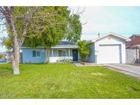 Charming light blue single-story home with a well-manicured lawn and attached garage at 702 E Dana Ave, Mesa, AZ 85204