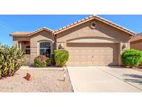 Tan one-story house with a two-car garage and desert landscaping at 20047 N 91St Ln, Peoria, AZ 85382