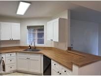 Bright kitchen with white cabinets, stainless steel sink and wood-look countertops offers a clean aesthetic at 3845 E Greenway Rd # 131, Phoenix, AZ 85032
