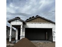 Exterior of home under construction shows open garage, covered porch and some roofing material at 5678 N 205Th Ln, Buckeye, AZ 85396