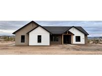 A charming single-story home featuring a combination of white and tan siding with sleek, dark-framed windows and a covered entryway at 1716 W Lucky Ln, Queen Creek, AZ 85144