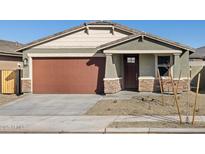 Single-story home with brown garage door, stone accents, and landscaping at 16014 W Cottontail Ln, Surprise, AZ 85387