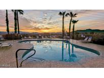 Community pool featuring a sunset view, palm trees, lounge chairs, and serene desert mountain views at 10401 N Saguaro Blvd # 224, Fountain Hills, AZ 85268