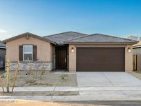 Charming single-story home features a brown two-car garage and a low maintenance gravel front yard at 22455 W Pontiac Dr, Surprise, AZ 85387