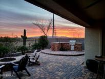 Brick paved patio with fire pit, BBQ, and seating area, overlooking sunset at 10637 W Eucalyptus Rd, Peoria, AZ 85383