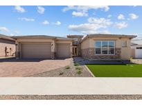 Charming single-story home featuring a brick driveway, three-car garage, and desert landscaping at 1021 W Ridge Rd, Apache Junction, AZ 85120