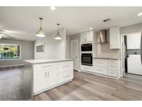 Open-concept kitchen featuring white cabinetry, stainless steel appliances and pendant lighting at 11133 W Cameo Dr, Sun City, AZ 85351