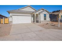 Charming one-story home with white exterior, stone accents, and a two-car garage at 40000 W Bunker Dr, Maricopa, AZ 85138