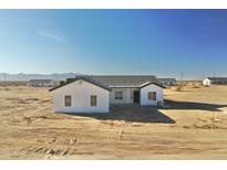 Charming single-story home featuring a modern design with white exterior and a gray tile roof under a clear blue sky at 25853 W Running Deer Trl, Wittmann, AZ 85361