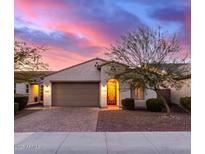 Beautiful stucco home with a 2-car garage and landscaped yard at sunset at 21950 N 100Th Ave, Peoria, AZ 85383