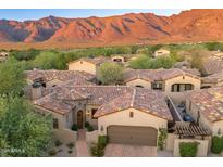 Stunning Tuscan-style home with colorful roof tiles and a lush, landscaped yard, set against a backdrop of majestic mountains at 3219 S Silverberry Ct, Gold Canyon, AZ 85118