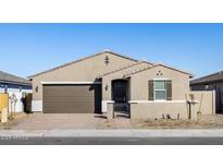 Tan house with brown garage door, black gate, and landscaping at 17738 W Coolidge St, Goodyear, AZ 85395