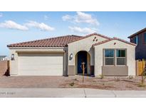 Single-story home featuring neutral stucco, a brick driveway, a two-car garage, and a red-tile roof at 5336 W Rainwater Dr, Laveen, AZ 85339