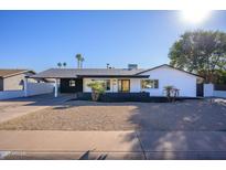 Updated mid-century modern home with a fresh white exterior, landscaping, and a long driveway at 3155 W Augusta Ave, Phoenix, AZ 85051