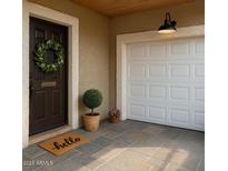 Inviting front entry with a dark door, wreath, charming hello doormat, and a white garage door at 1859 N Morris --, Mesa, AZ 85201