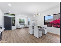 Stylish living and dining area with bright natural light, wood floors, and elegant chandelier at 10646 E Butherus Dr, Scottsdale, AZ 85255