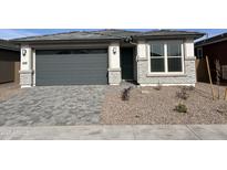 Charming single-story home featuring a gray garage door, brick accents, and low-maintenance desert landscaping at 39980 W Elm Dr, Maricopa, AZ 85138