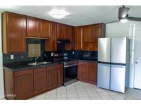 This kitchen boasts wood cabinets, sleek black countertops, and modern stainless-steel appliances at 2007 N 67Th Dr, Phoenix, AZ 85035