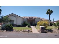 Charming single-story home featuring a manicured lawn, mature trees, and a stone-accented facade at 18029 W San Miguel Ave, Litchfield Park, AZ 85340