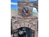 Brick outdoor fireplace with decorative wreath and fire tools at 6908 W Sunnyside Dr, Peoria, AZ 85345