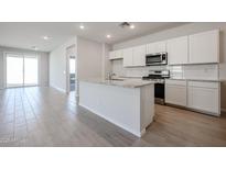 Modern kitchen with white cabinets, granite countertops, stainless steel appliances, and an island with a sink at 39980 W Bravo Dr, Maricopa, AZ 85138