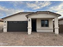 Charming single-story home featuring a brick driveway, a two-car garage, and a covered front porch at 39985 W Elm Dr, Maricopa, AZ 85138