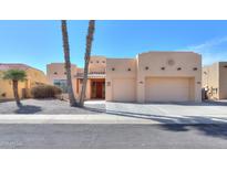 Beige stucco home with a two car garage, desert landscaping and palm trees at 923 W Crooked Stick Dr, Casa Grande, AZ 85122