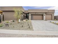 Stunning modern home with a desert landscape, stone accents, and a spacious driveway leading to a two-car garage at 37200 N Cave Creek Rd # 1023, Scottsdale, AZ 85262