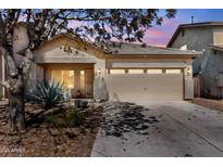 Charming single-story home featuring a neutral stucco exterior, a two-car garage, and desert landscaping at 44032 W Garden Ln, Maricopa, AZ 85139