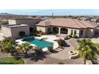 Expansive backyard with a pool, firepit, and manicured landscaping on a custom home at 19517 W Huron Ln, Buckeye, AZ 85326