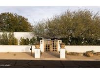 White stucco house with wood gate and landscaping at 12801 N 65Th Pl, Scottsdale, AZ 85254